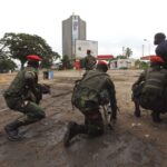 Congolese security officers position themselves as they secure the street near the state television headquarters in Kinshasa